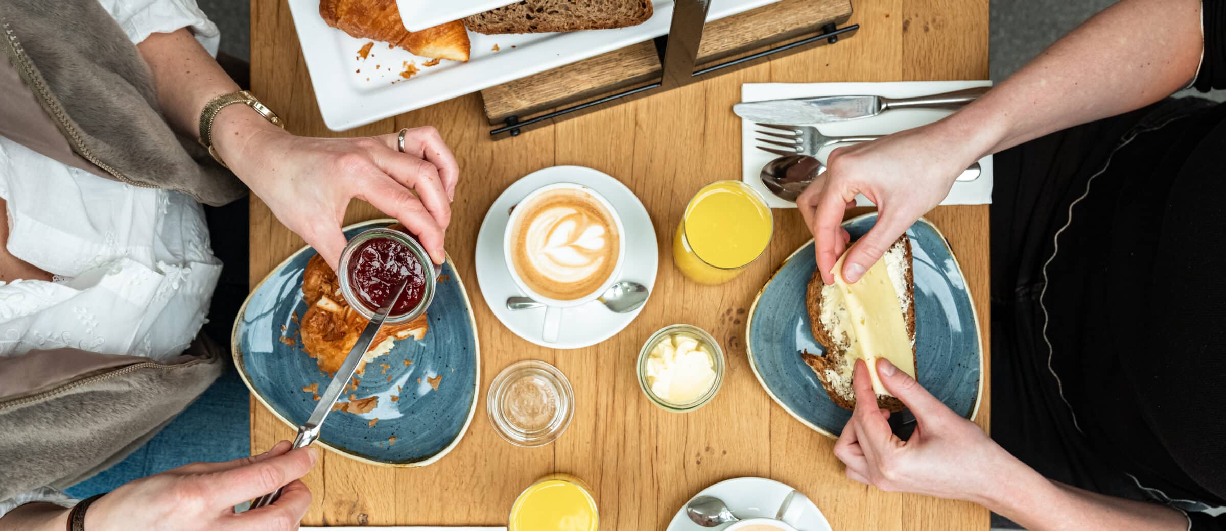 een volle ontbijttafel met verschillende brood en beleg opties.