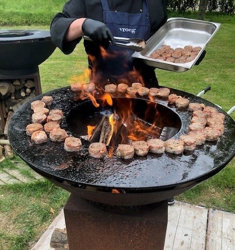 hamburgers op een ronde grilplaat en een chef die ze erop ligt