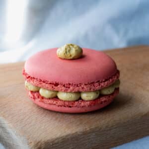 een roze macaron met een groene creme vulling